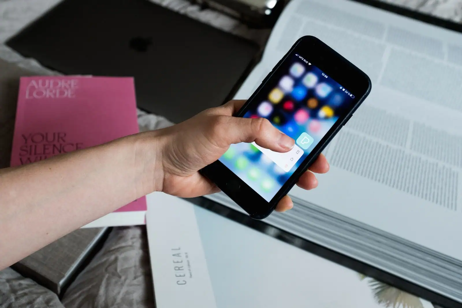 Main tenant un smartphone affichant un fil d'actualité