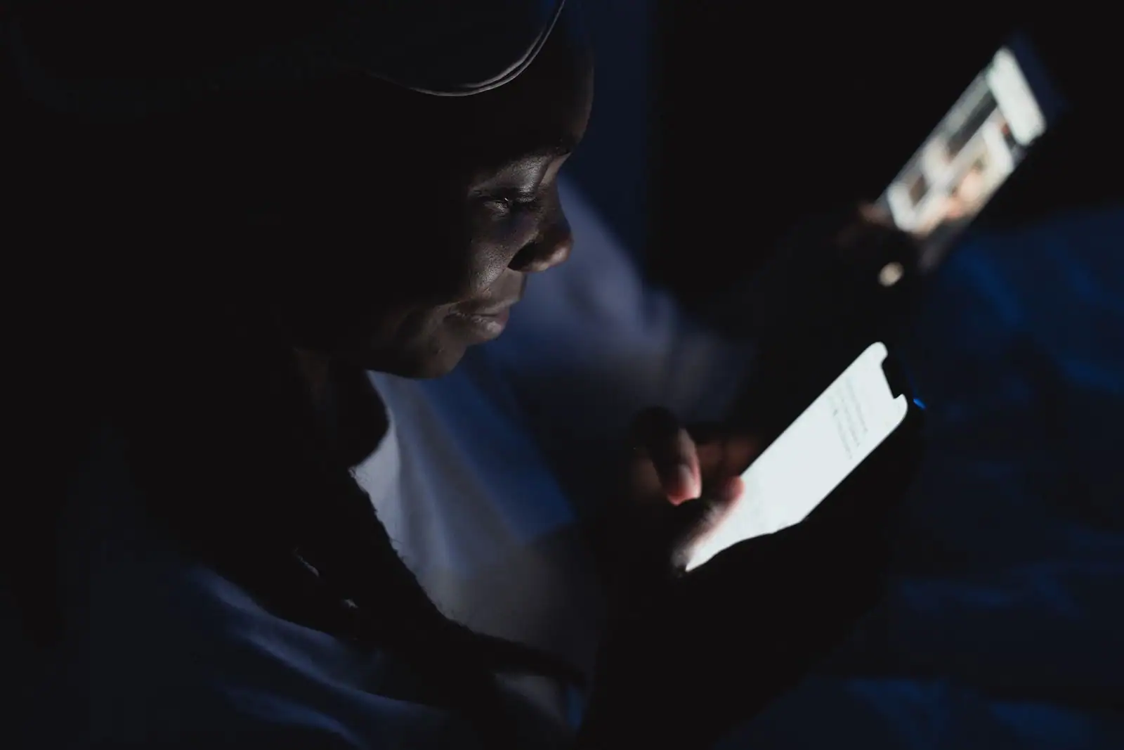Personne lisant sur l'écran lumineux de son smartphone dans la pénombre d'une soirée