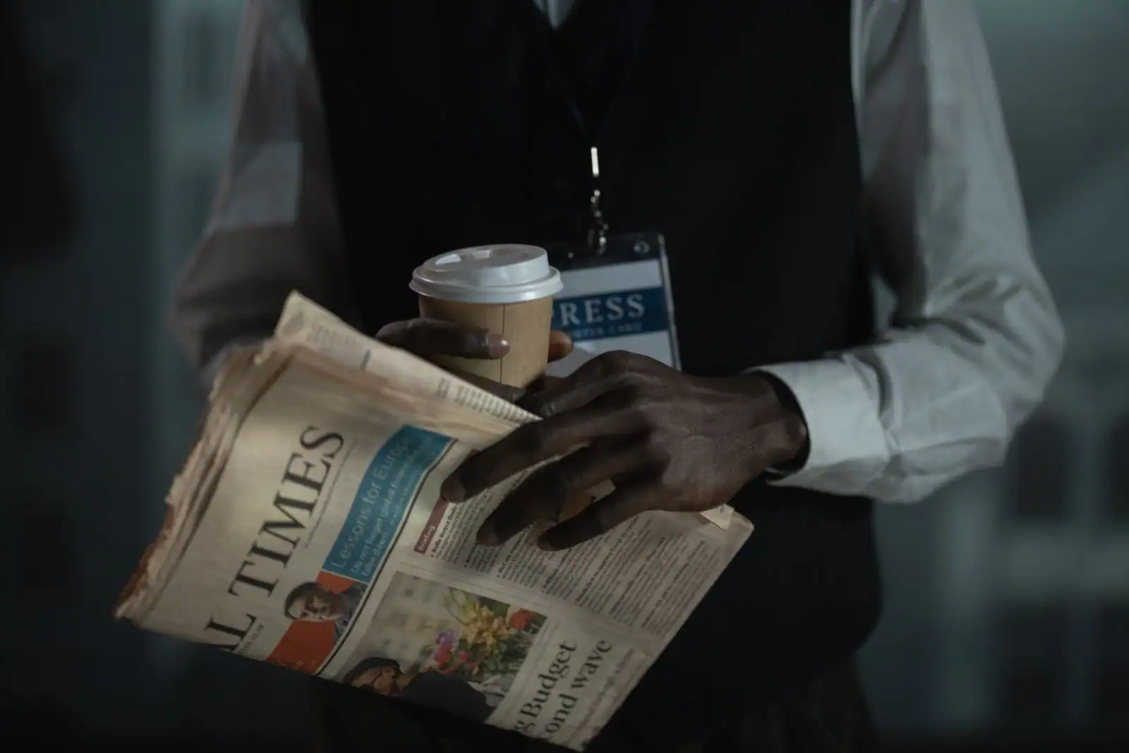 Personne lisant les titres de l'actualité dans un journal imprimé tenu entre les mains