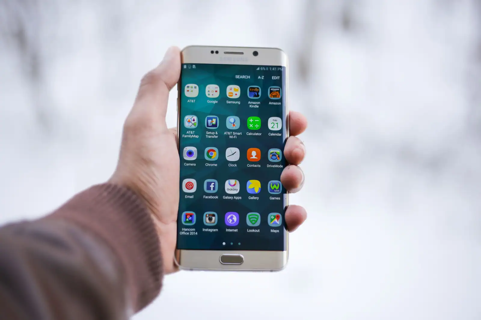 Main tenant un smartphone Samsung sous Android affichant une grille d'icônes d'applications