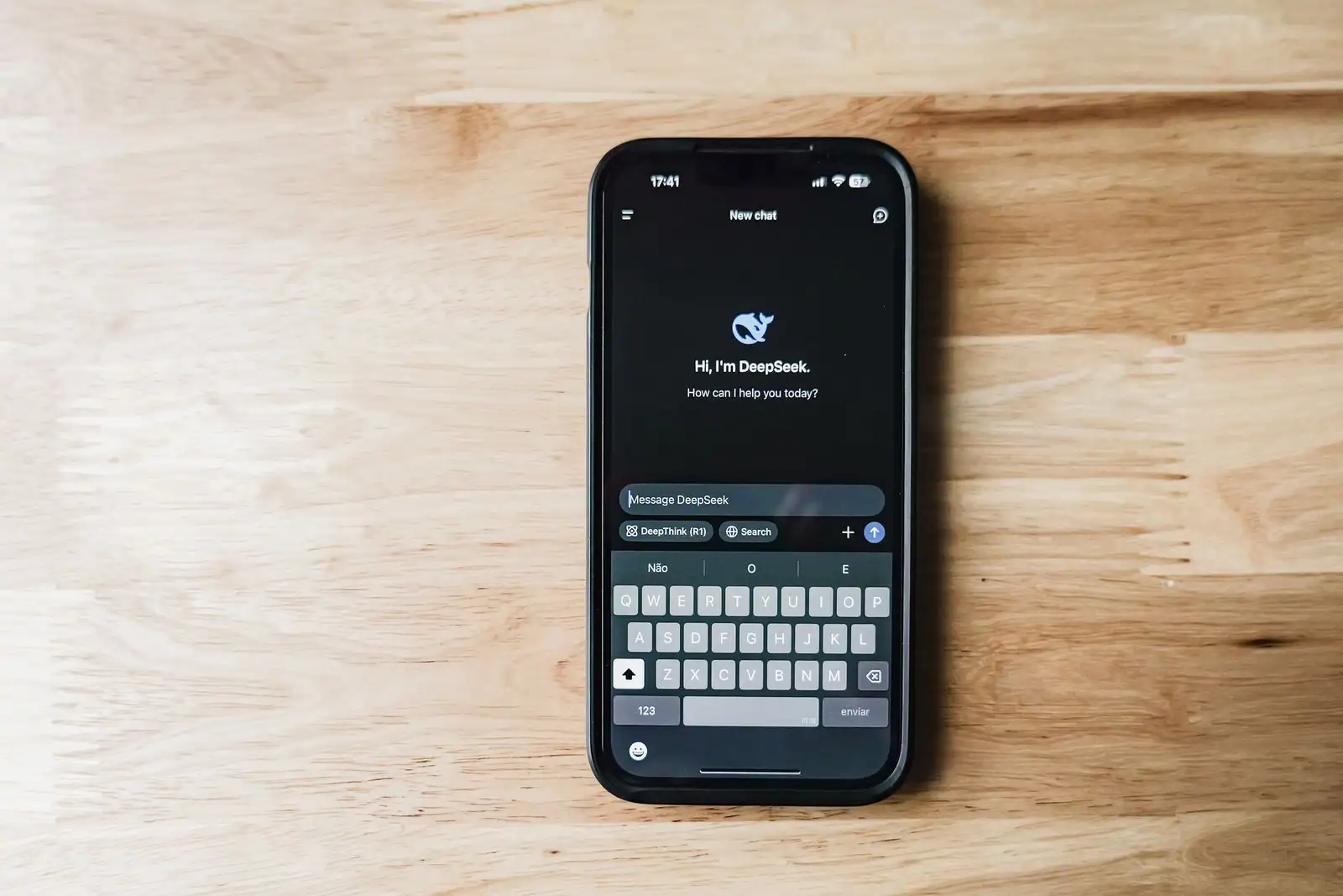 Smartphone posé sur une table en bois affichant l'application DeepSeek et son message d'accueil.