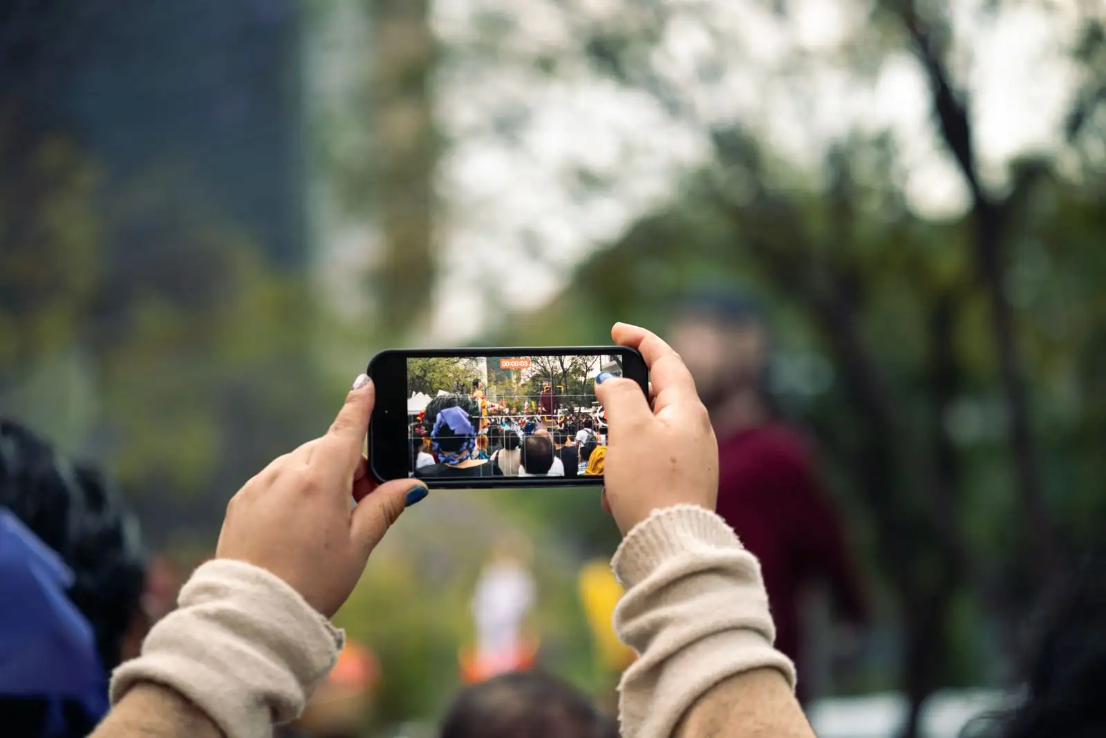 Mains tenant un smartphone pour capturer une scène en extérieur avec son appareil photo