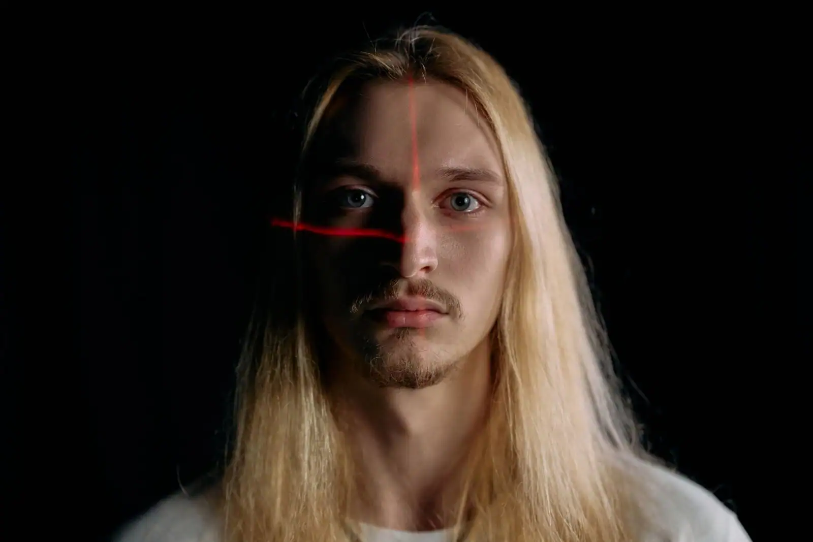 Visage d'un homme traversé par des lignes laser rouges, évoquant un scan de reconnaissance faciale