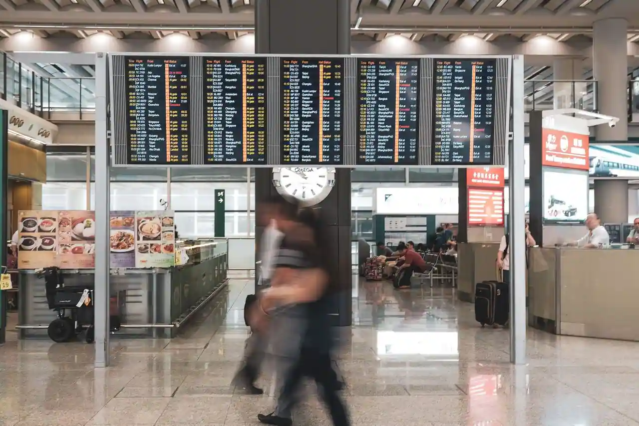 Hall d'un terminal d'aéroport avec les panneaux d'affichage des vols et des voyageurs en transit