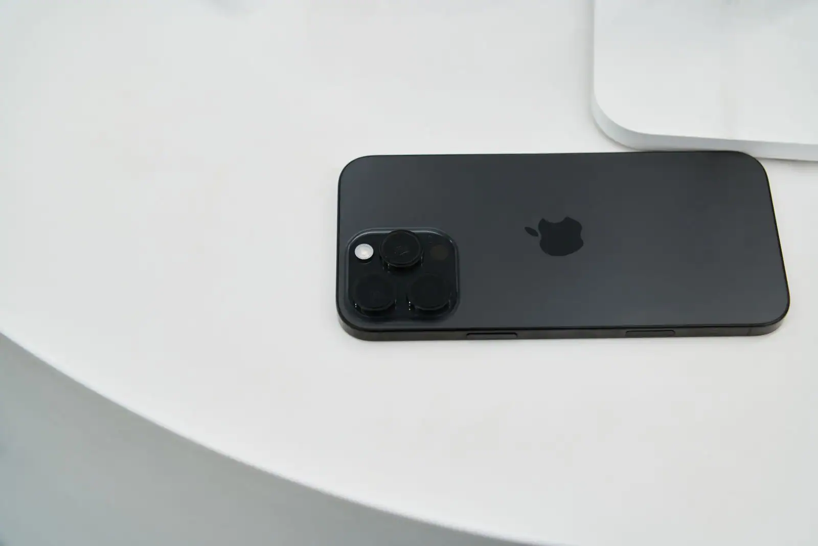 Smartphone noir posé sur une table blanche, montrant son bloc photo arrière à trois objectifs