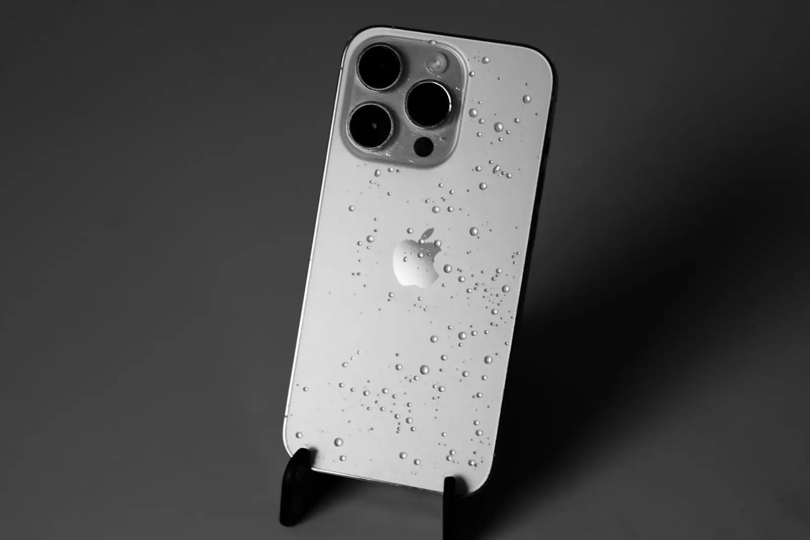 iPhone vu de dos couvert de gouttes d'eau, illustrant la résistance à l'eau d'un téléphone