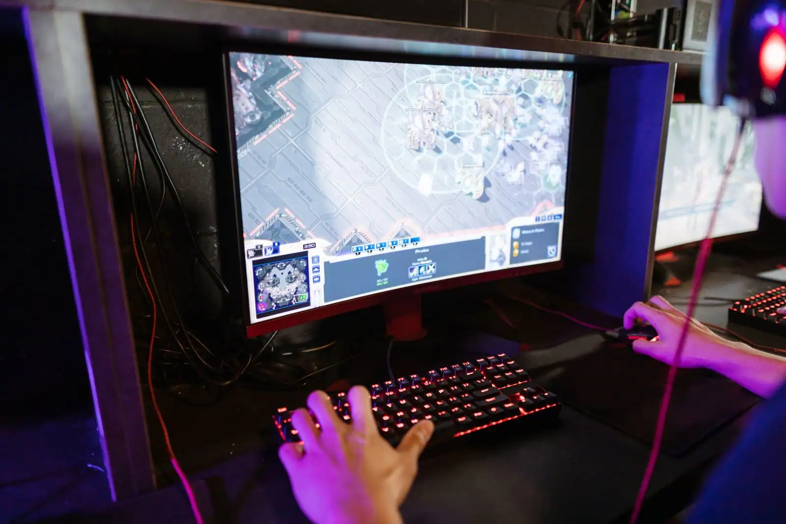 Personne jouant à un jeu vidéo sur un ordinateur, devant un clavier de jeu rétroéclairé