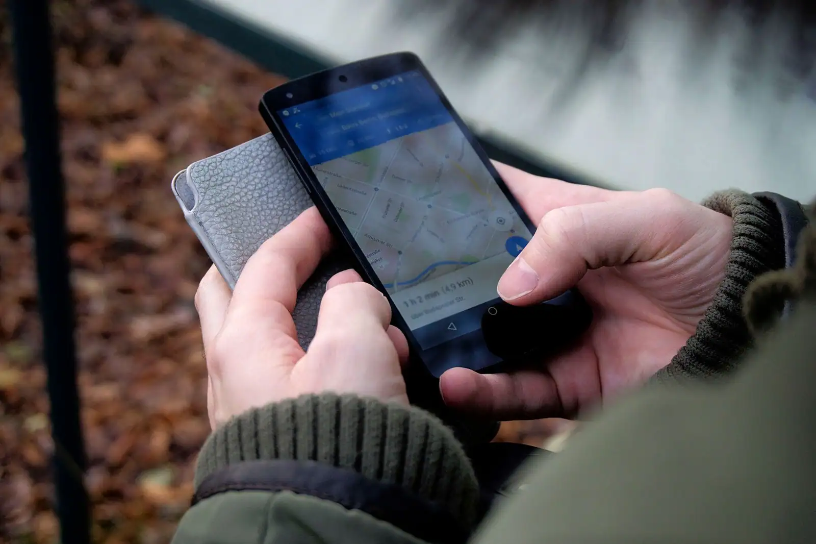 Smartphone tenu à deux mains affichant une application de carte avec un point de position bleu à l'écran.