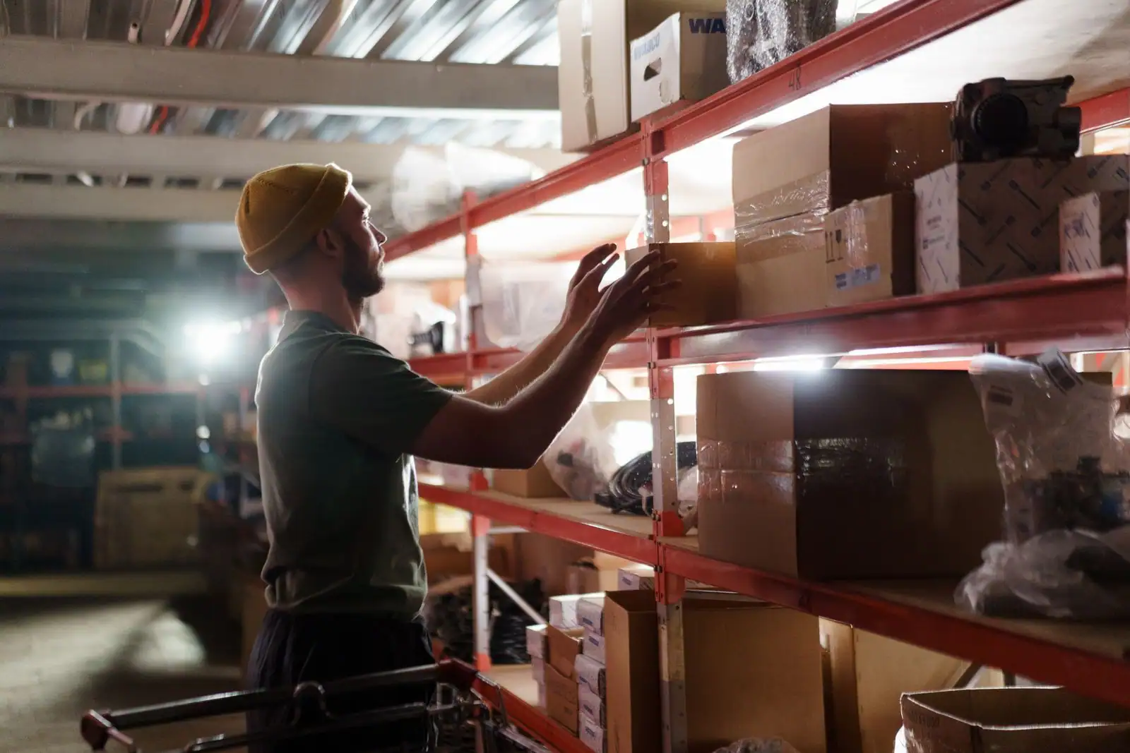 Magasinier attrapant un carton sur une étagère dans un entrepôt de stockage