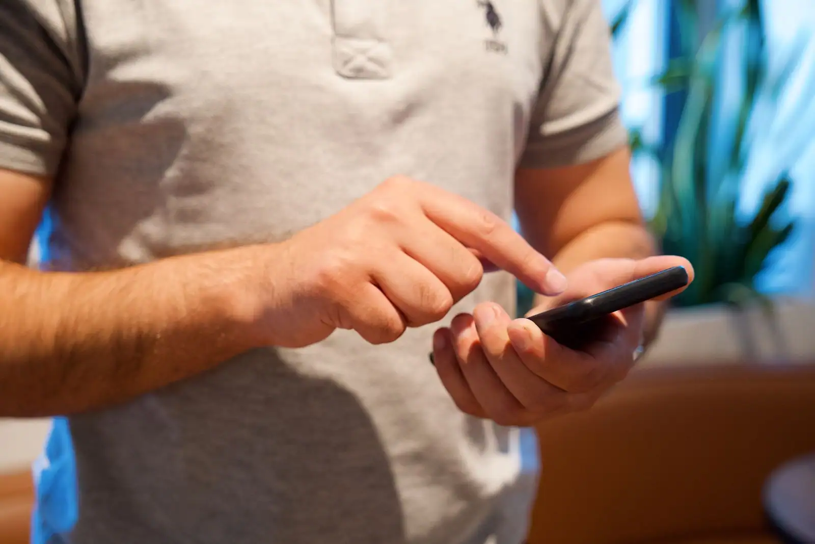 Personne utilisant une application sur smartphone dans son salon.