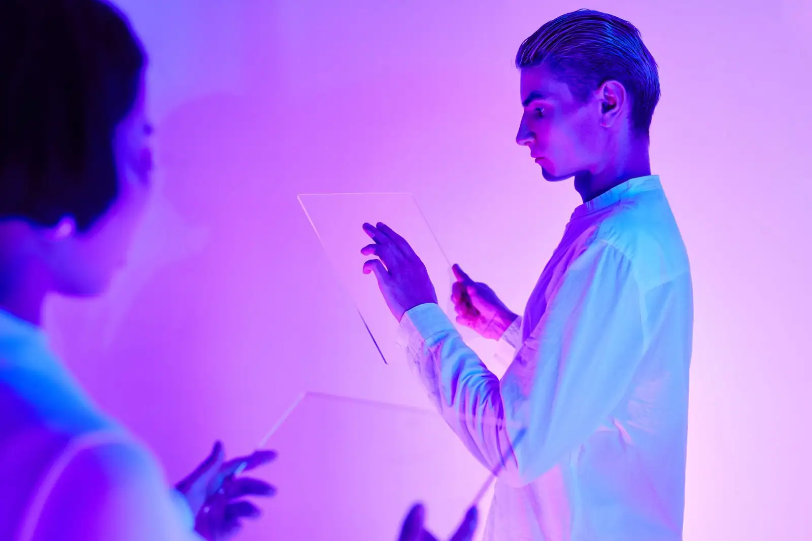 Homme effleurant un écran tactile transparent futuriste sous une lumière néon violette