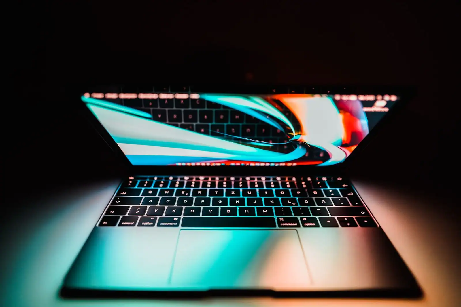 Ordinateur portable ouvert dans la pénombre, clavier rétroéclairé et écran allumé.