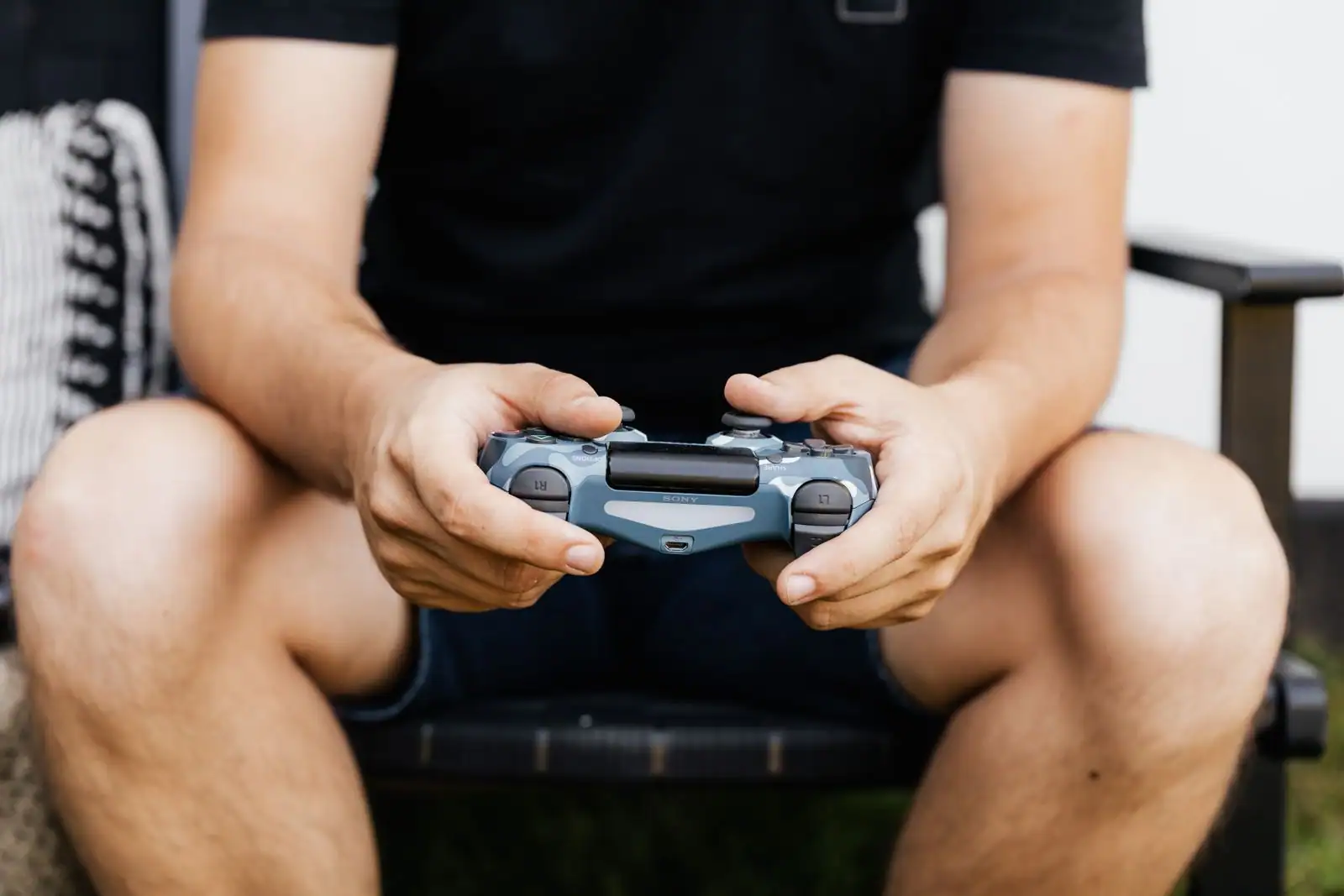 Mains d'un joueur tenant une manette PlayStation Sony en gros plan, pendant une partie de jeu vidéo.