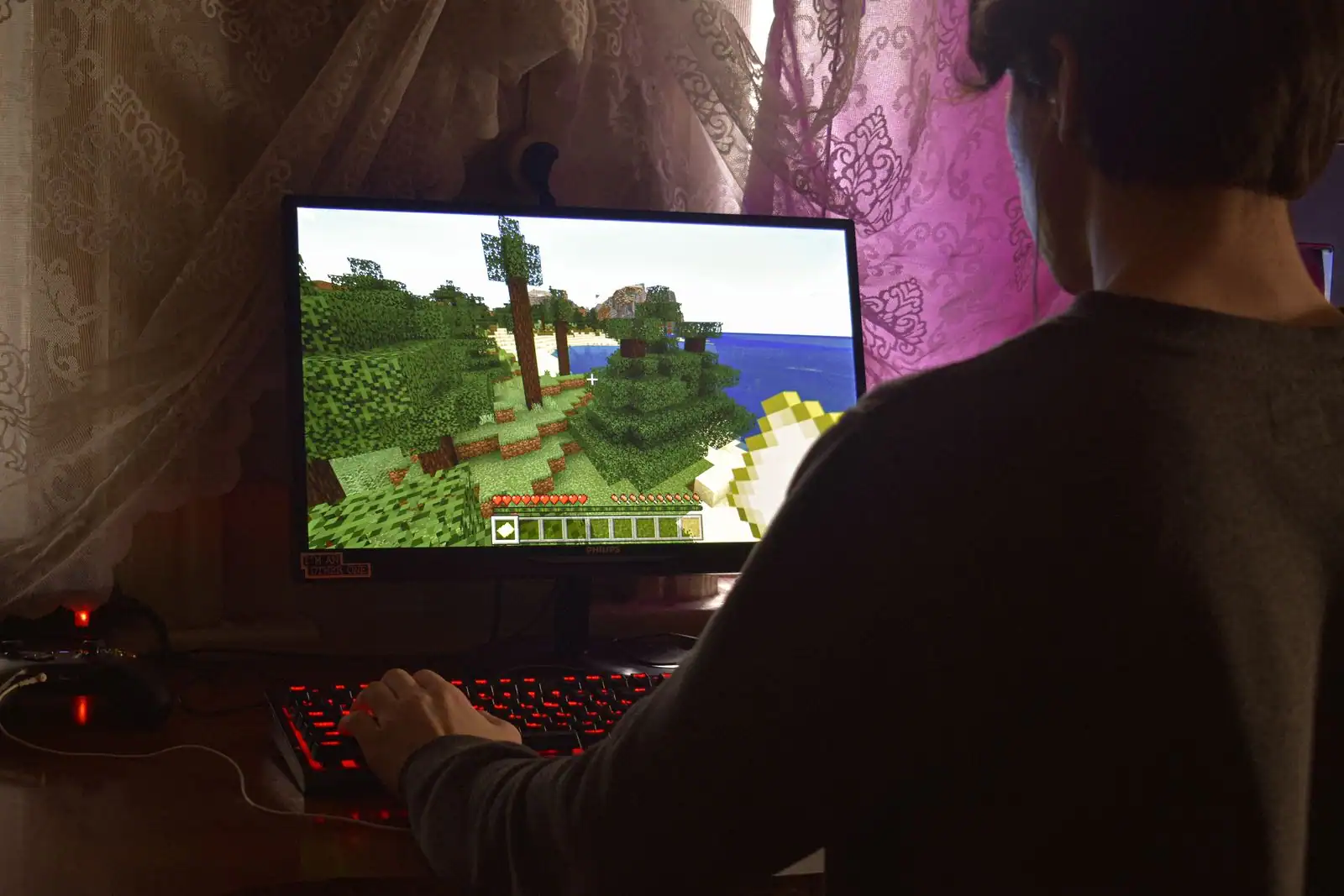 Jeune joueur concentré devant l'écran d'un jeu vidéo, baigné dans une lumière colorée.