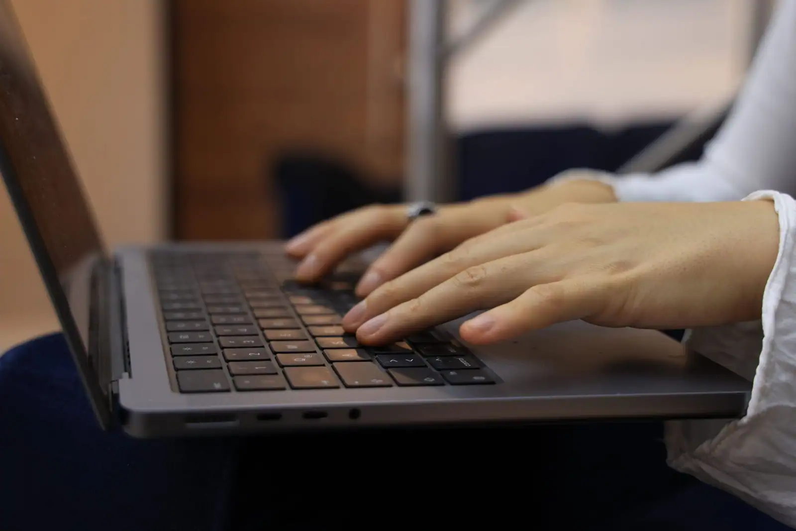Mains d'une personne en train de taper sur le clavier d'un ordinateur portable, en intérieur.
