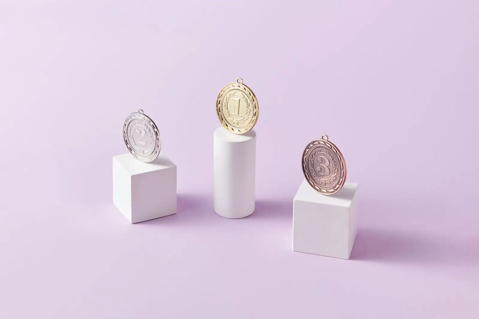 Médailles d'or, d'argent et de bronze posées sur des podiums numérotés, évoquant un classement sportif.