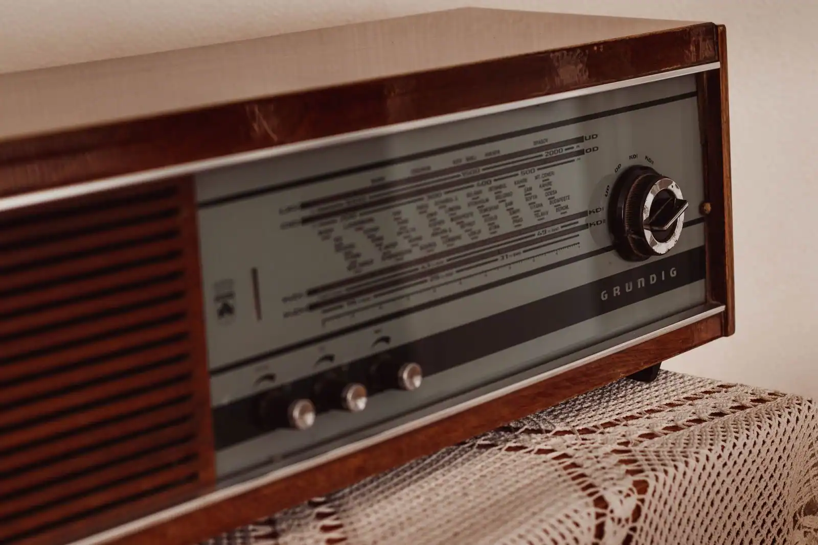 Poste de radio vintage en bois avec cadran et molette de réglage, posé sur un napperon