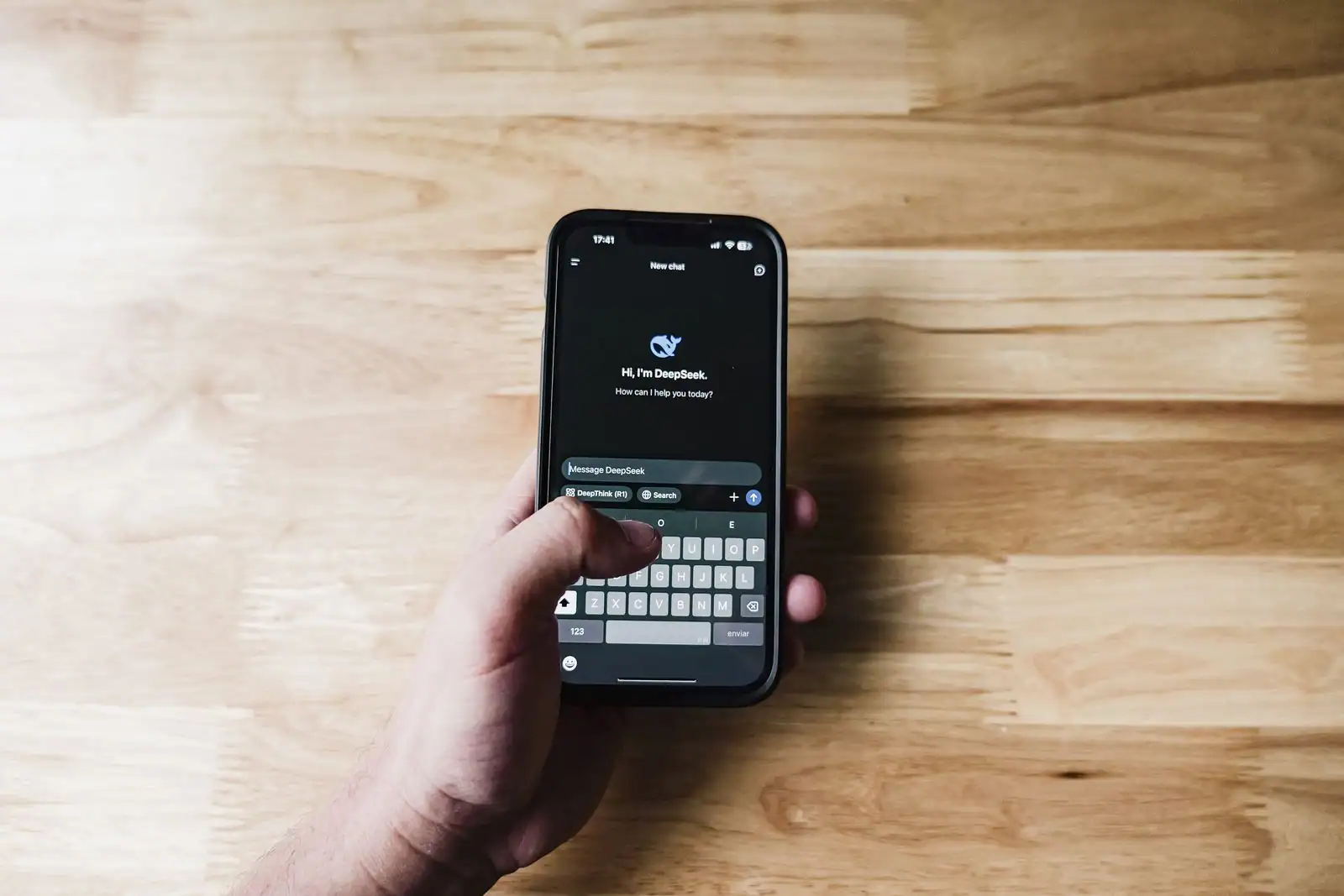 Une personne utilise un assistant IA sur l’écran de son smartphone, tenu en main.