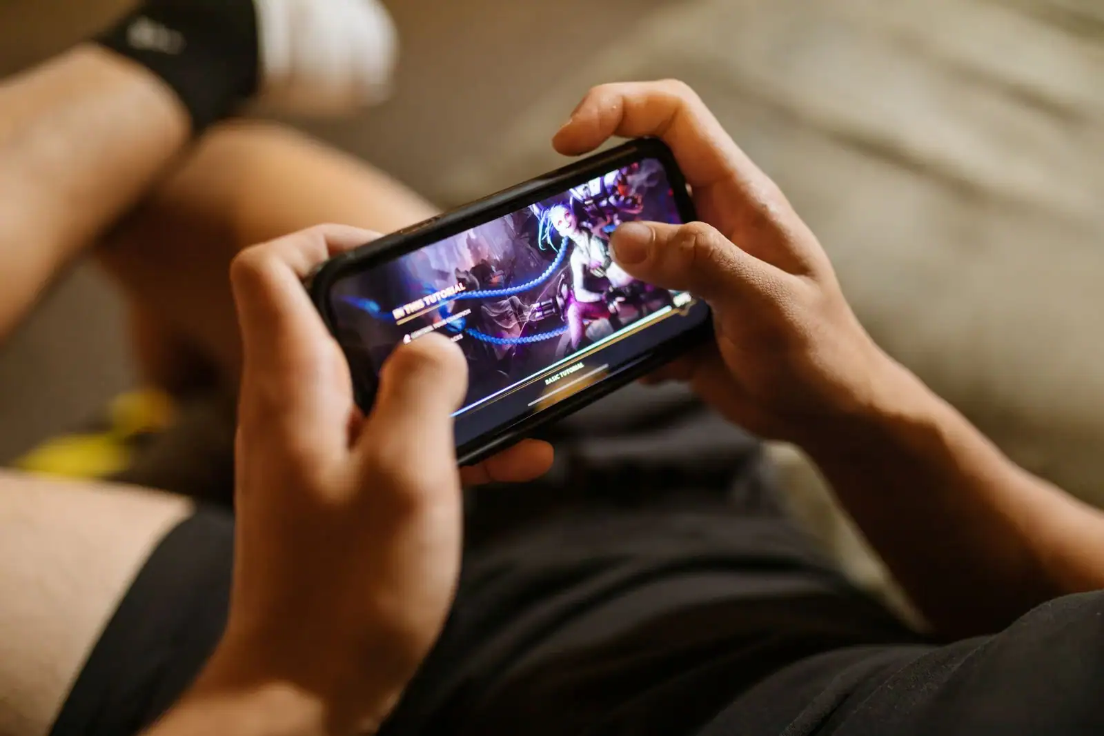 Personne jouant à un jeu mobile sur son smartphone tenu à l'horizontale à deux mains