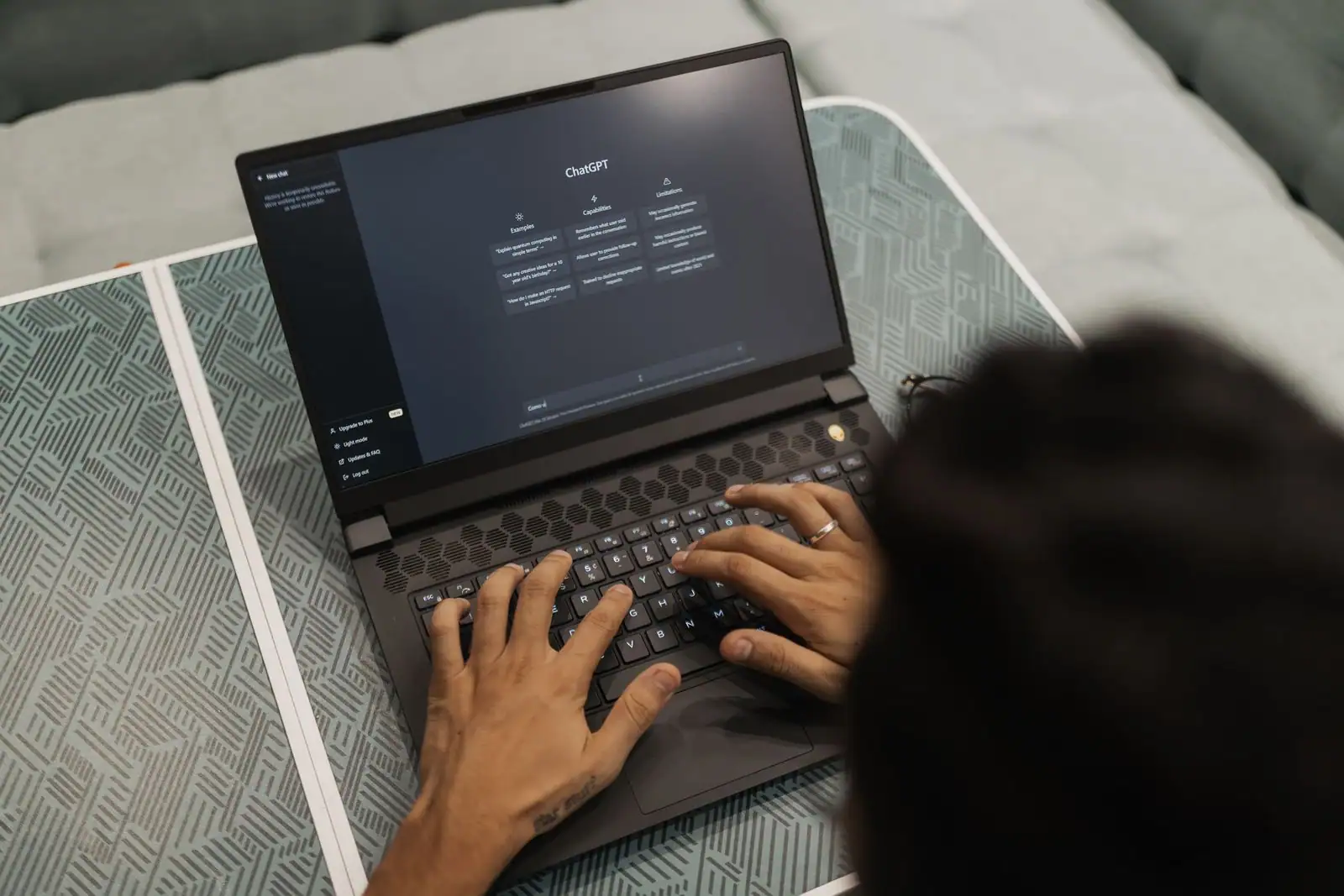 Une personne tape sur un ordinateur portable dont l'écran affiche l'interface de ChatGPT