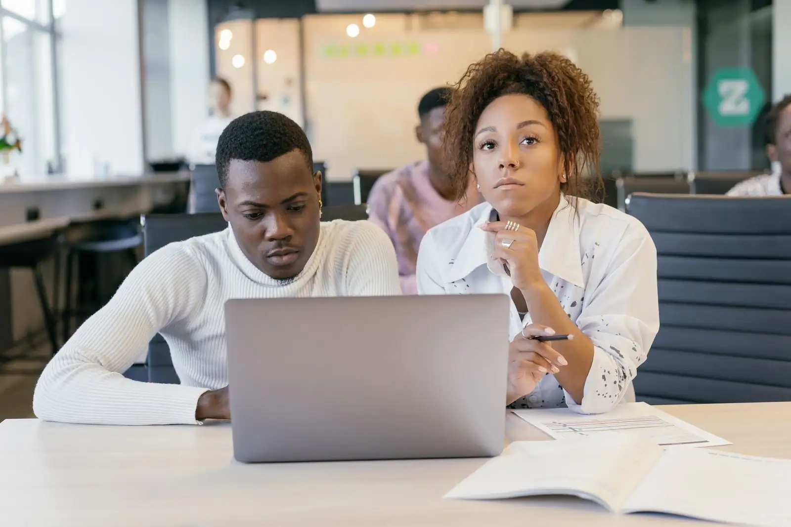 Deux collègues concentrés devant un ordinateur portable dans un bureau partagé