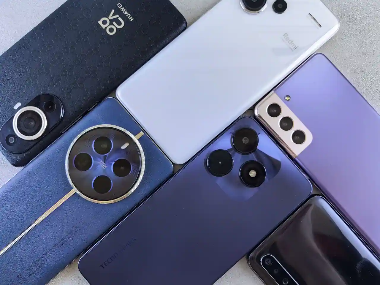 Plusieurs smartphones de marques différentes empilés, montrant leurs modules photo au dos