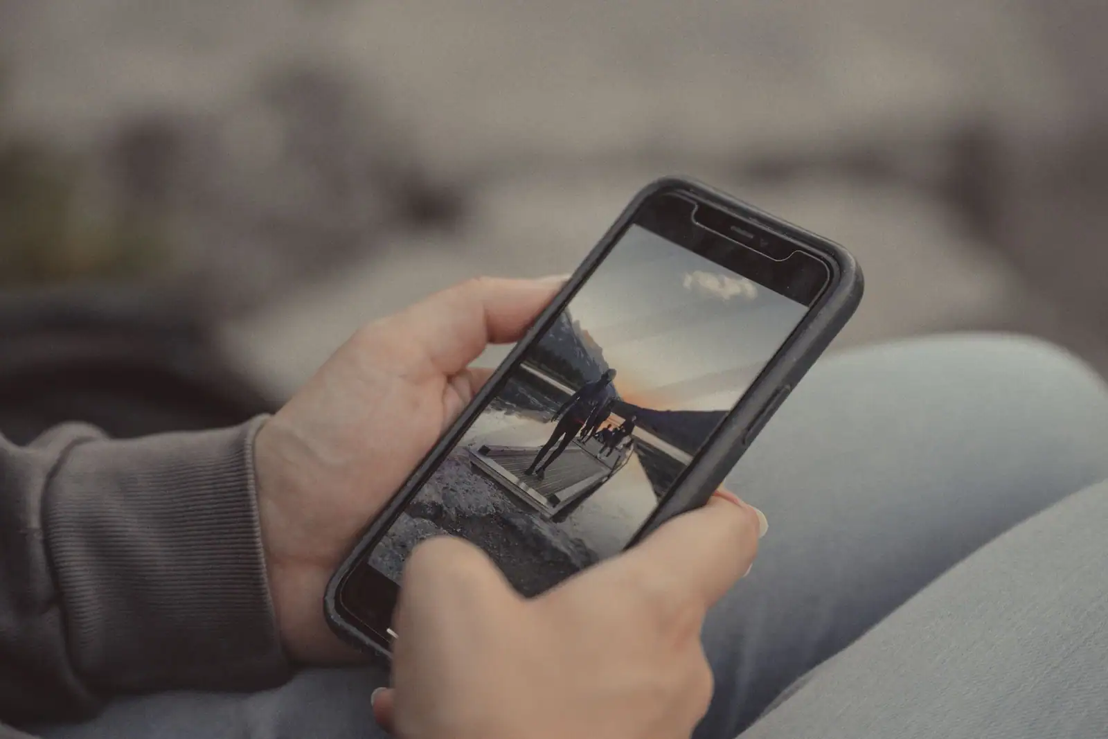 Personne tenant un smartphone moderne à la main, l'écran affichant une photo