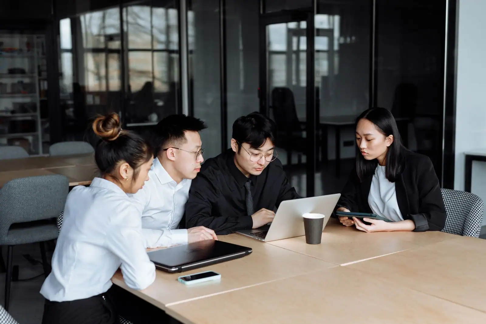 Une équipe collabore autour d'un ordinateur portable dans un espace de travail en entreprise.
