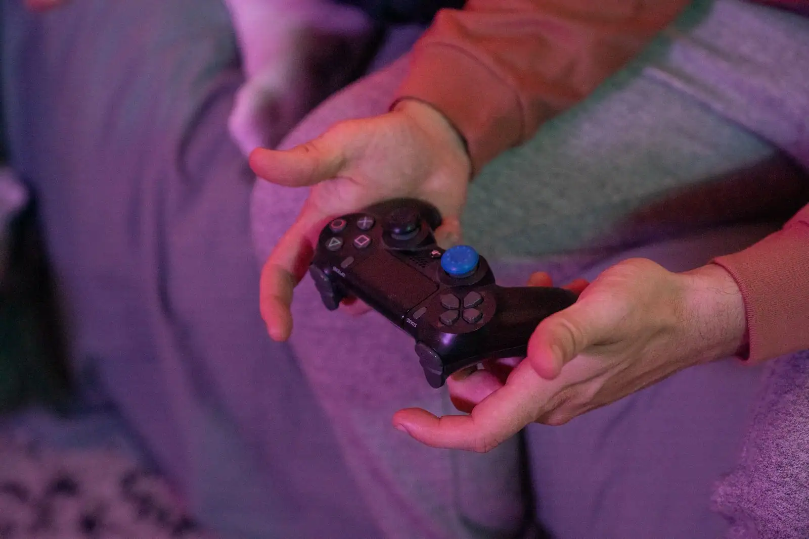Gros plan sur une manette de console PlayStation tenue à deux mains pendant une partie