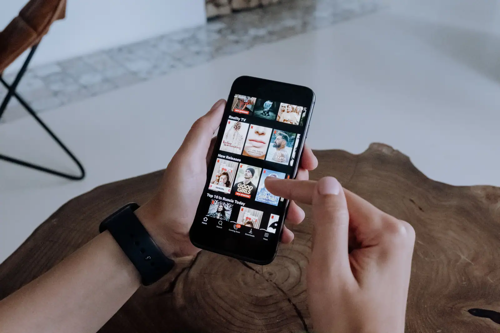 Main parcourant une liste de vidéos sur l'écran d'un smartphone à la recherche d'un contenu