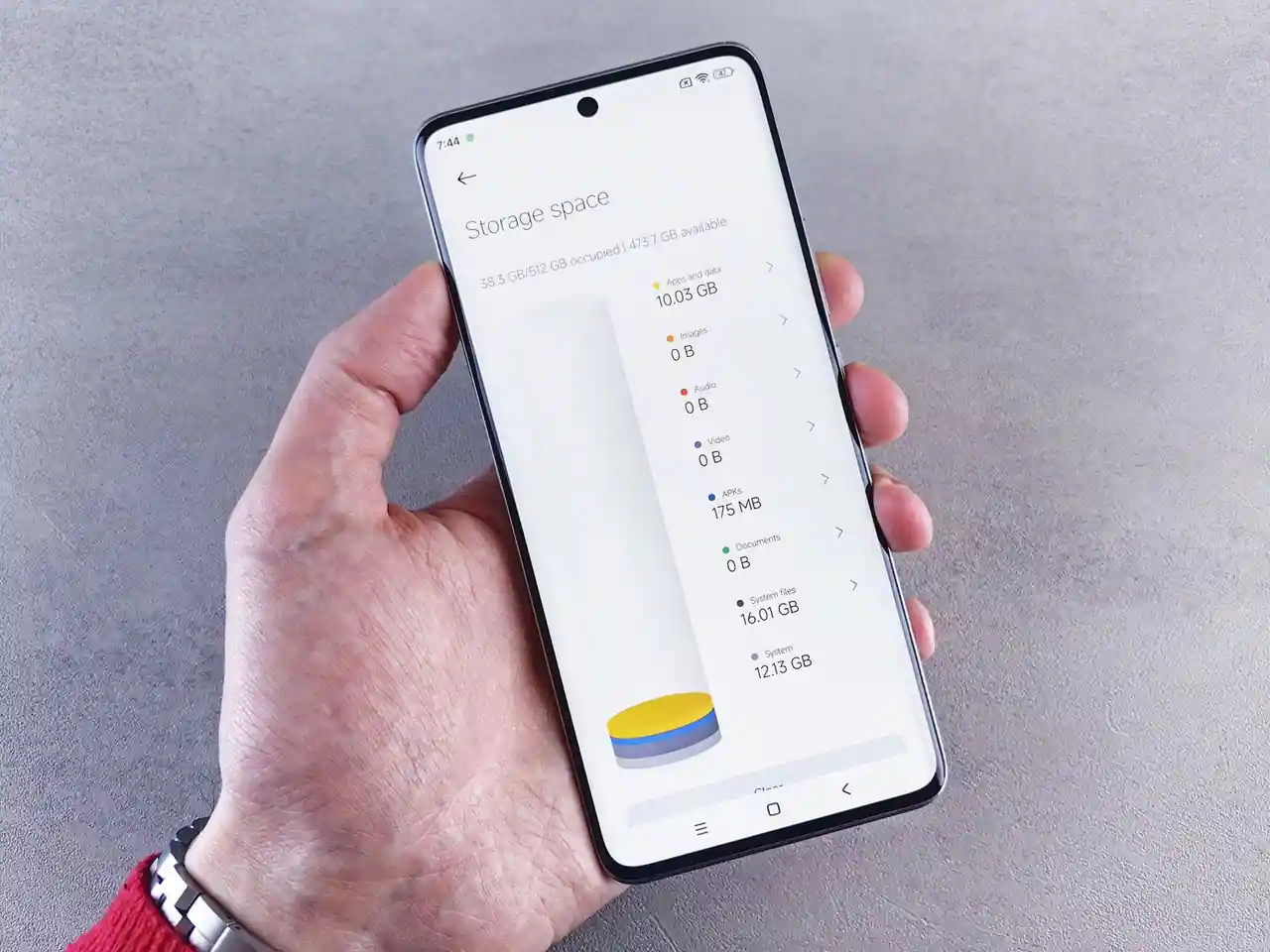 Main tenant un smartphone dont l'écran affiche l'espace de stockage occupé, applications en tête