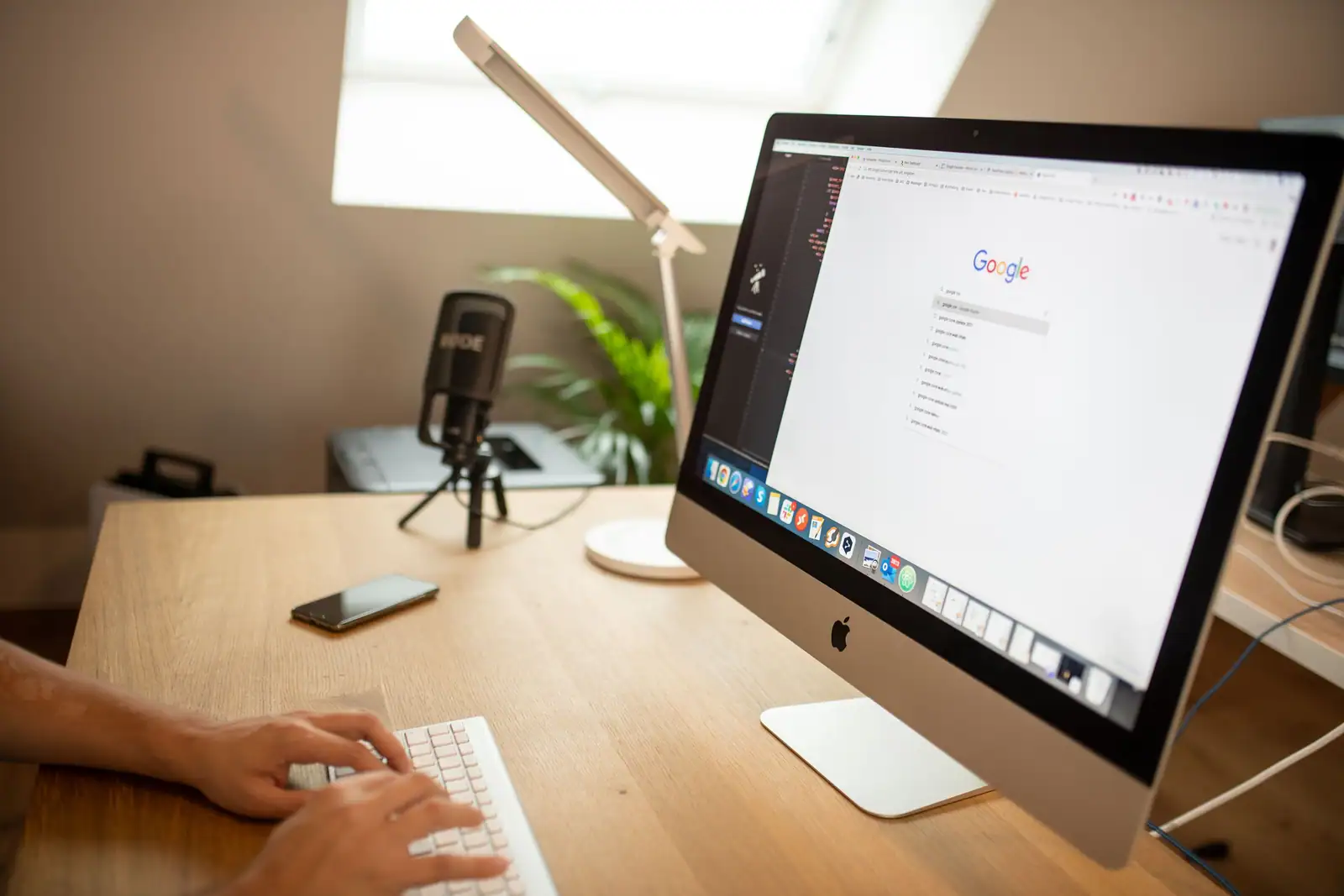 Un poste de travail avec un grand écran ouvert sur une page Google, un clavier et un smartphone.