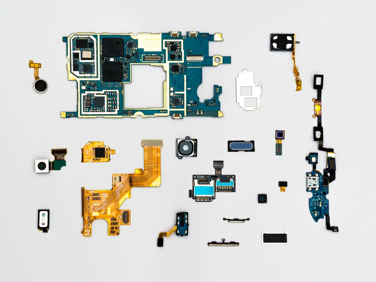 Les composants internes d'un smartphone démonté, carte mère et modules photo posés à plat.