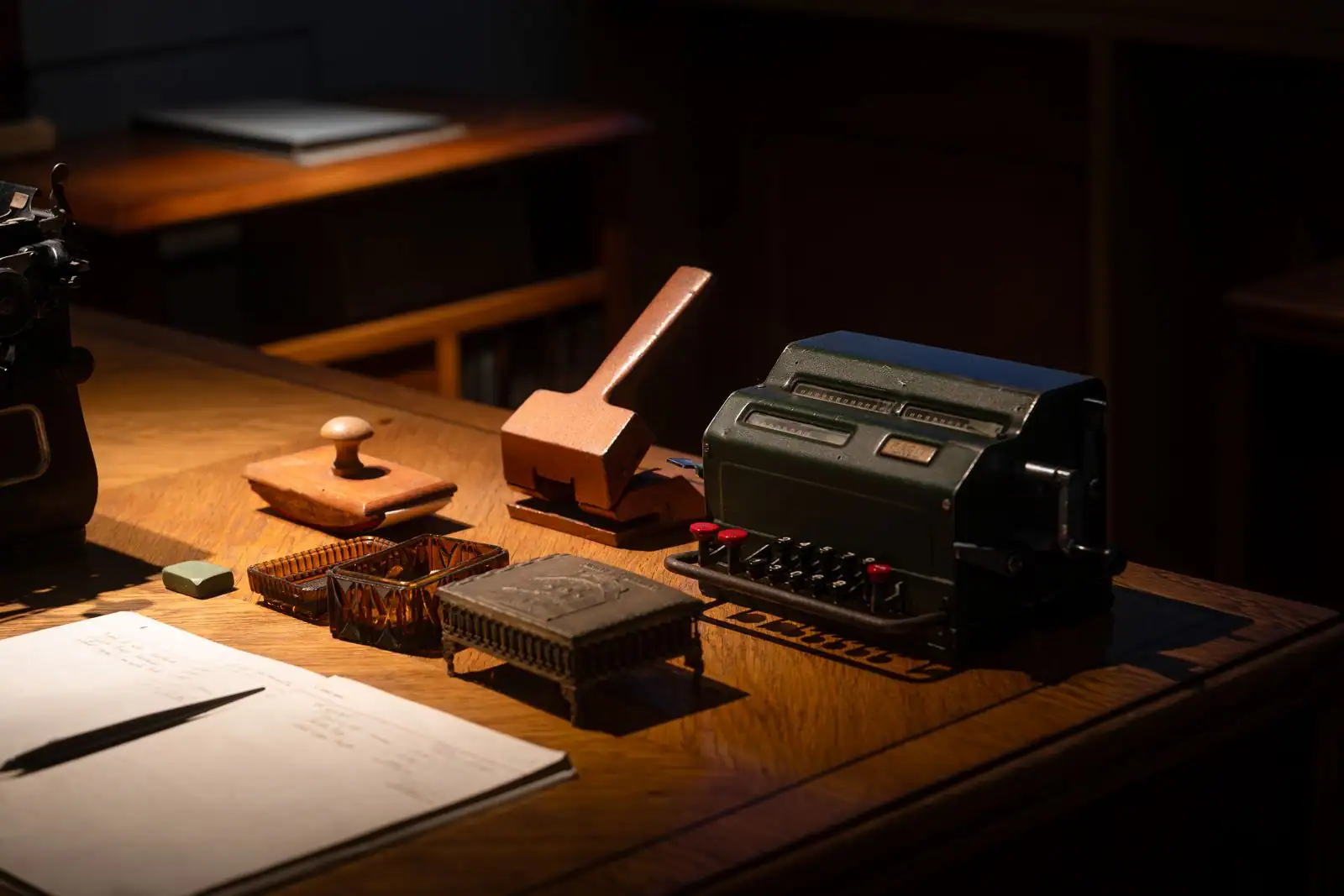 Ancienne machine à calculer mécanique et ses rangées de touches numérotées, sur un bureau en bois